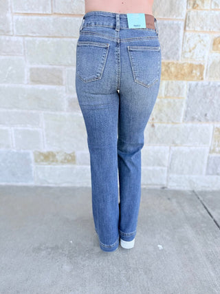 Person wearing blue jeans with a stone wall background