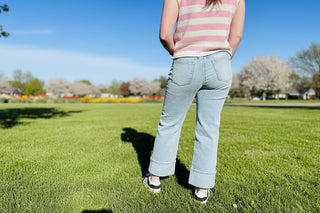 Person wearing light blue jeans and a striped shirt standing.