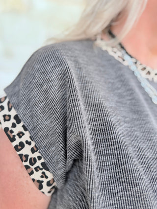 Gray ribbed sweater with leopard print trim on a blurred background