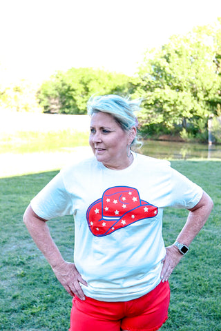 Person wearing a white t-shirt with a red and blue graphic design outdoors.