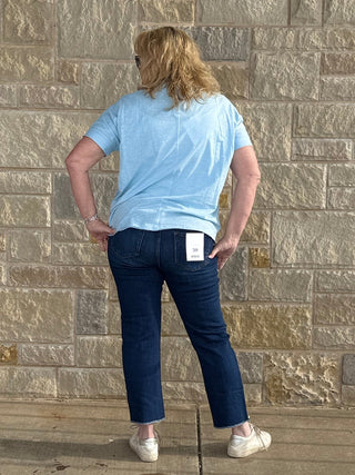 Person standing on a wooden deck with a stone wall background