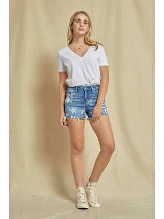 A pair of high-waisted denim shorts with star print detail, worn by a female model.