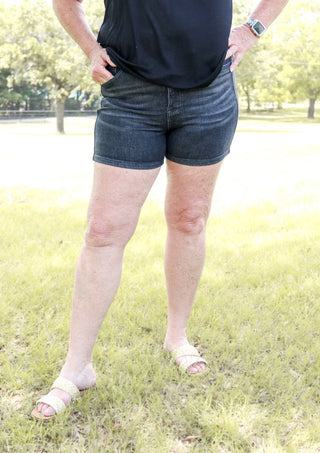 Person wearing blue denim shorts standing on grass with a blurred background