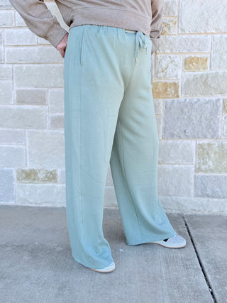 Person wearing light blue pants standing against a brick wall.