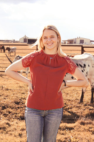 Woman in a red blouse standing in front of cows on a farm