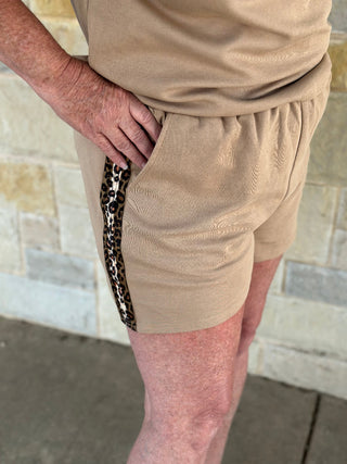 Beige shorts with a leopard print side stripe worn by a person.