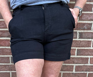 Person wearing navy shorts standing against a brick wall