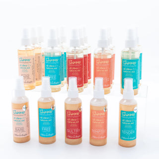 A collection of Mixologie Shimmer Moisturizing Body Mist spray bottles in various colors.
