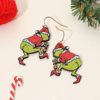 Christmas-themed earrings resembling a character in a red suit and green body, with a candy cane and wreath in the background.