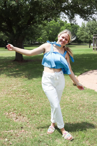 Woman in a blue top and white pants standing in a park