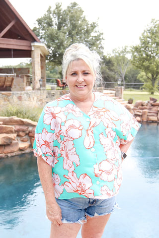 wearing a green and white floral print knit top with three-quarter sleeves and a V-neck.