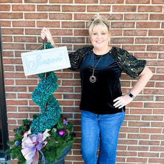 Woman holding a sign with 'Seasons' in front of a brick wall