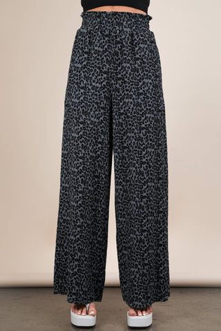 Leopard print pants worn by a person on a beige background