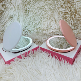 Two round mirrors with pink and white bases on a fluffy white surface