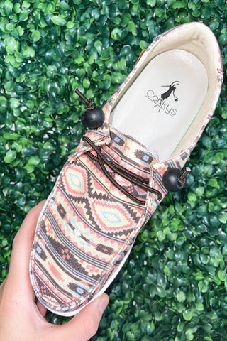 Patterned shoe held by a hand with a green grass background