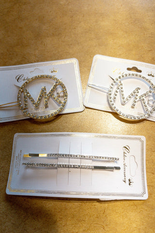 Decorative hair accessories with 'M' design on gold surface